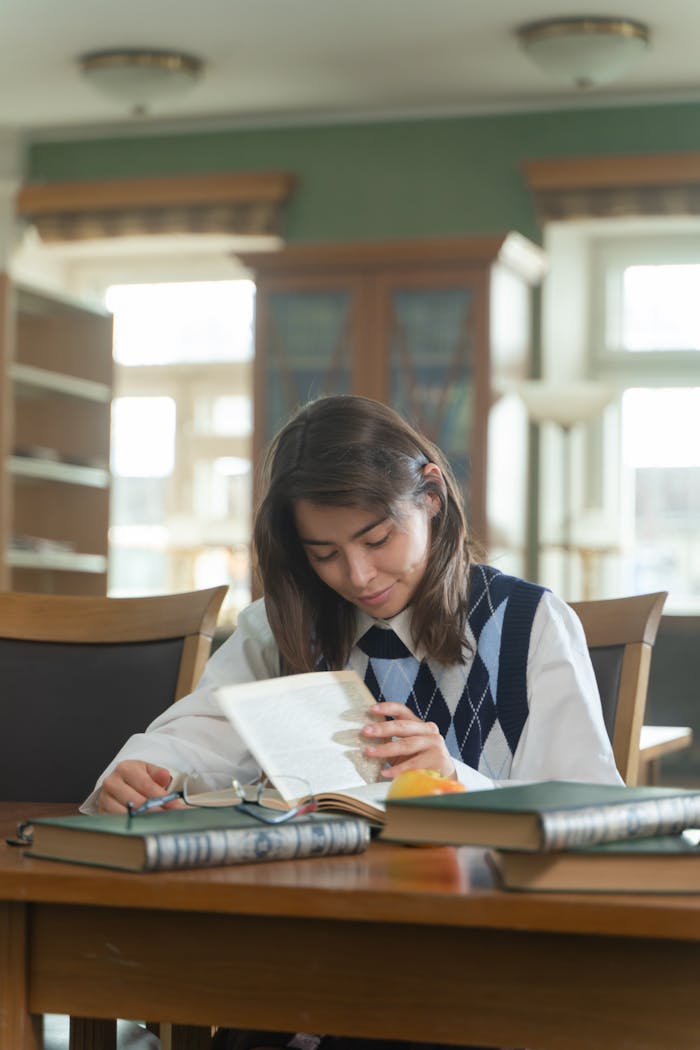 team-04 Young student immersed in reading at a library, surrounded by books, and engaging in focused study.