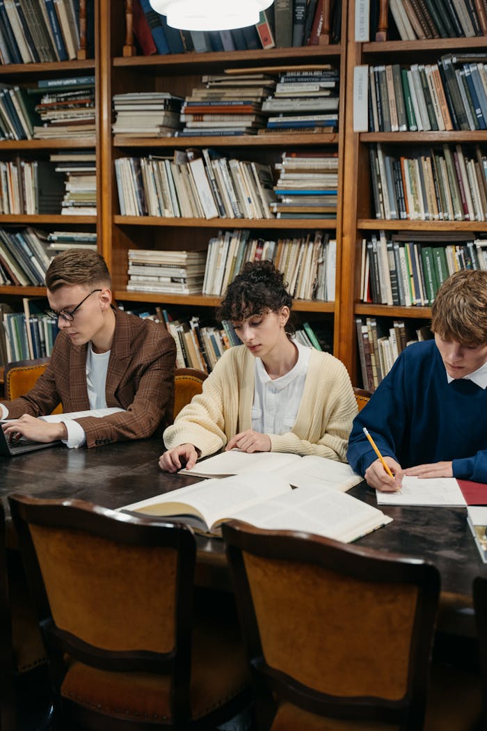 team-03 Students focused on studying in a university library filled with bookshelves.